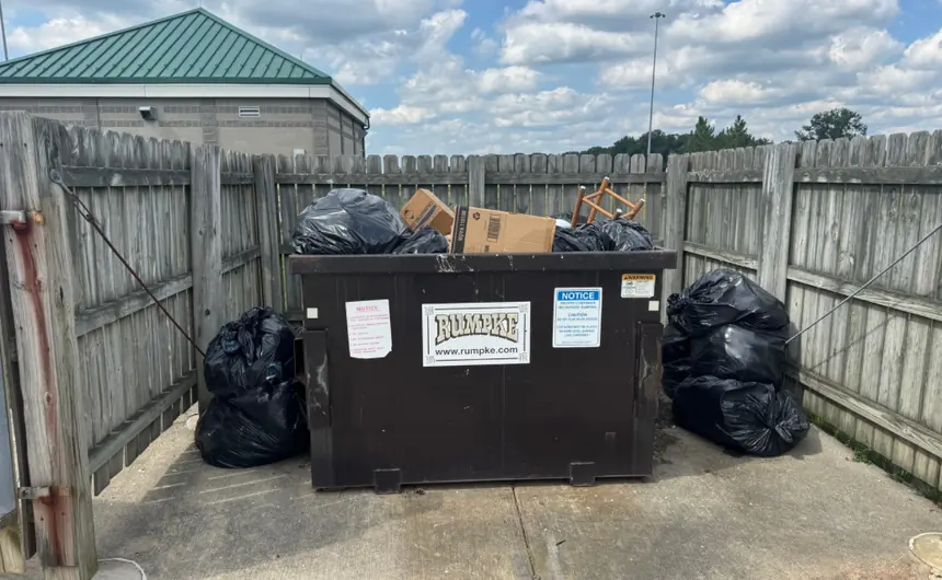 An overflowing commercial dumpster pad before pickup.