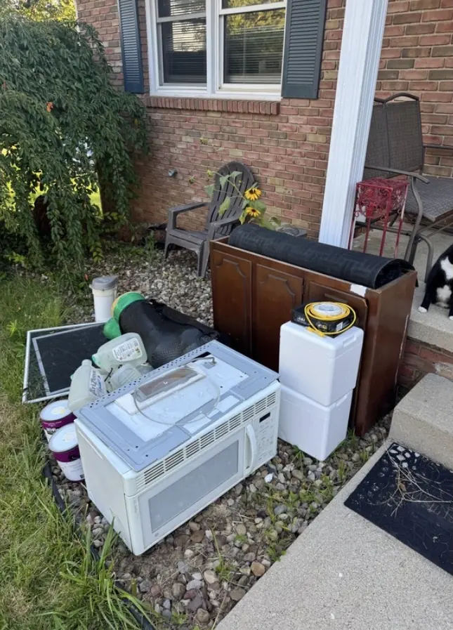 Before: a microwave, a cabinet, foam coolers and paint cans piled by a porch.